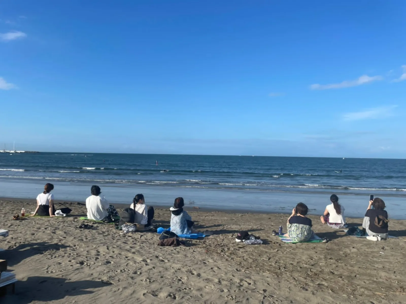 浜辺で海を眺めながら座る参加者たち